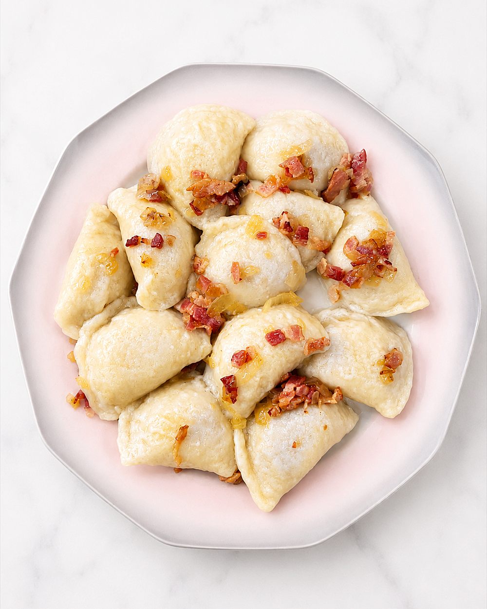 A plate of pierogi topped with crisp bacon and sauteed onion.